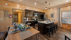 A wooden cabin interior with a kitchen, dining area, and a small bar. - SummerFun! Pets, Indoor Pool, Fire Pit, Hot Tub, Foosball/Air Hockey, Dollywood! (Sevierville)