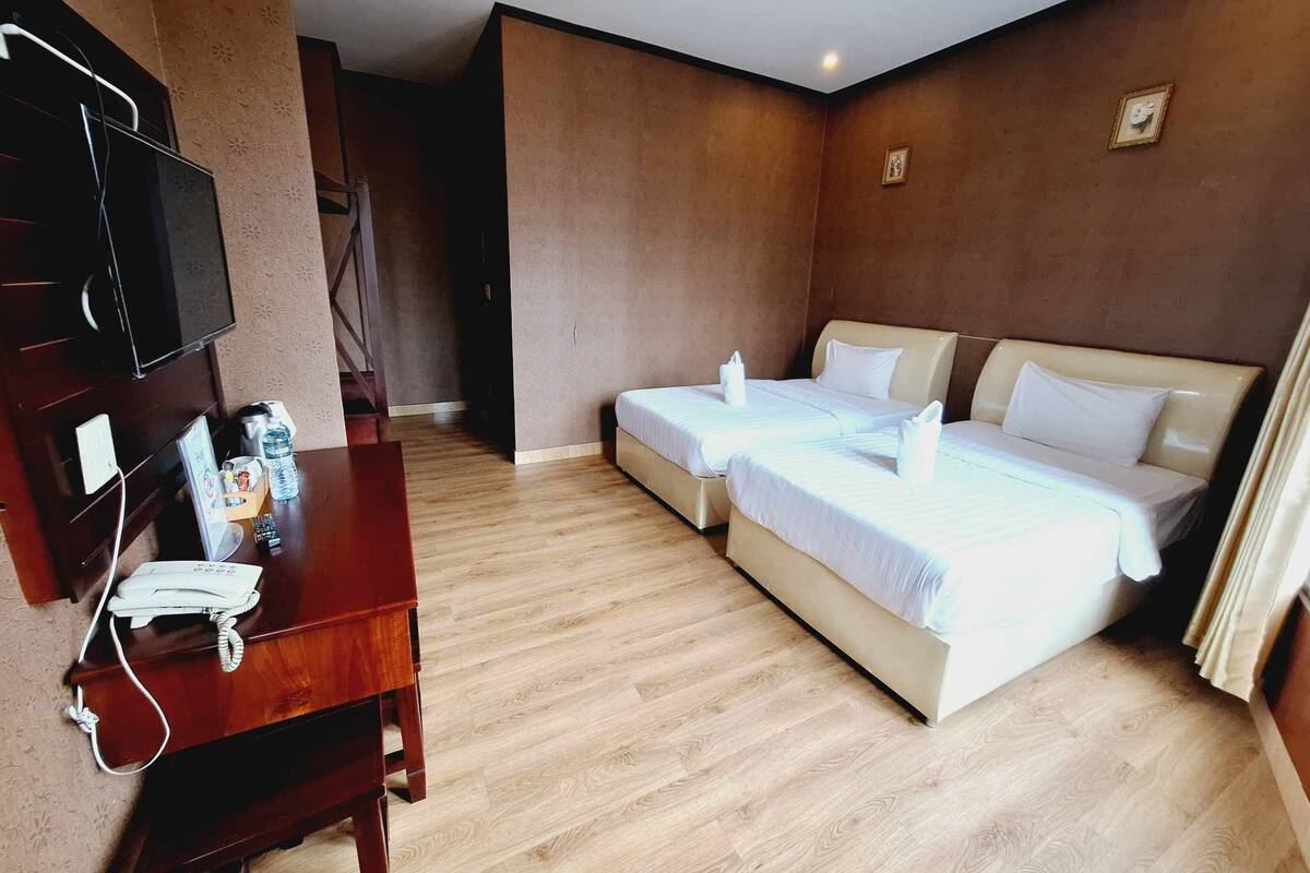 Een hotelkamer met twee bedden, een bureau met telefoon en een televisie.