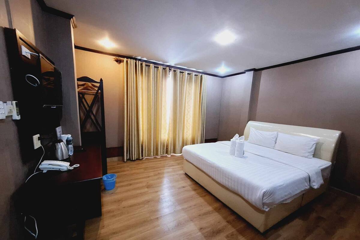 Een hotelkamer met een bed, een bureau met telefoon en een spiegel.