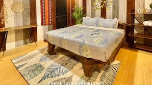 A bedroom with a large bed, wooden headboard, and a decorative mirror. - Punta Isla Lake Resort (Lake Sebu)