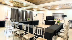 A conference room with a long table, white chairs, a whiteboard, a projector, and a speaker. - Punta Isla Lake Resort (Lake Sebu)