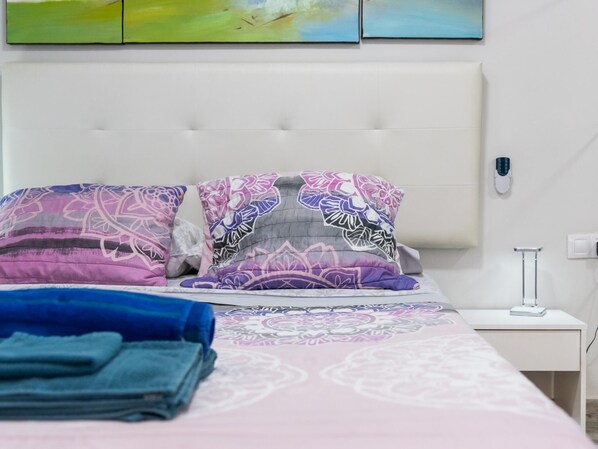 Un lit bien fait, avec des coussins à motifs et une serviette bleue pliée posée sur le côté.