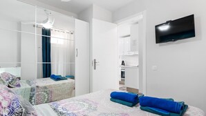Ett hotellrum med en säng, en TV, en garderob och en spegel.