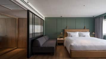 Una habitación de hotel moderna con una cama grande, un sofá, un armario y una mesita de noche.