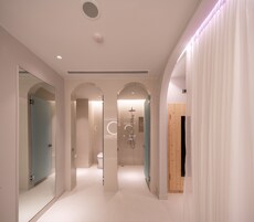 Ein moderner Hotelkorridor mit Glastüren, einer Dusche und einer Holztür.