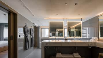 A modern hotel bathroom with a large mirror, dual sinks, and a vanity with towels.