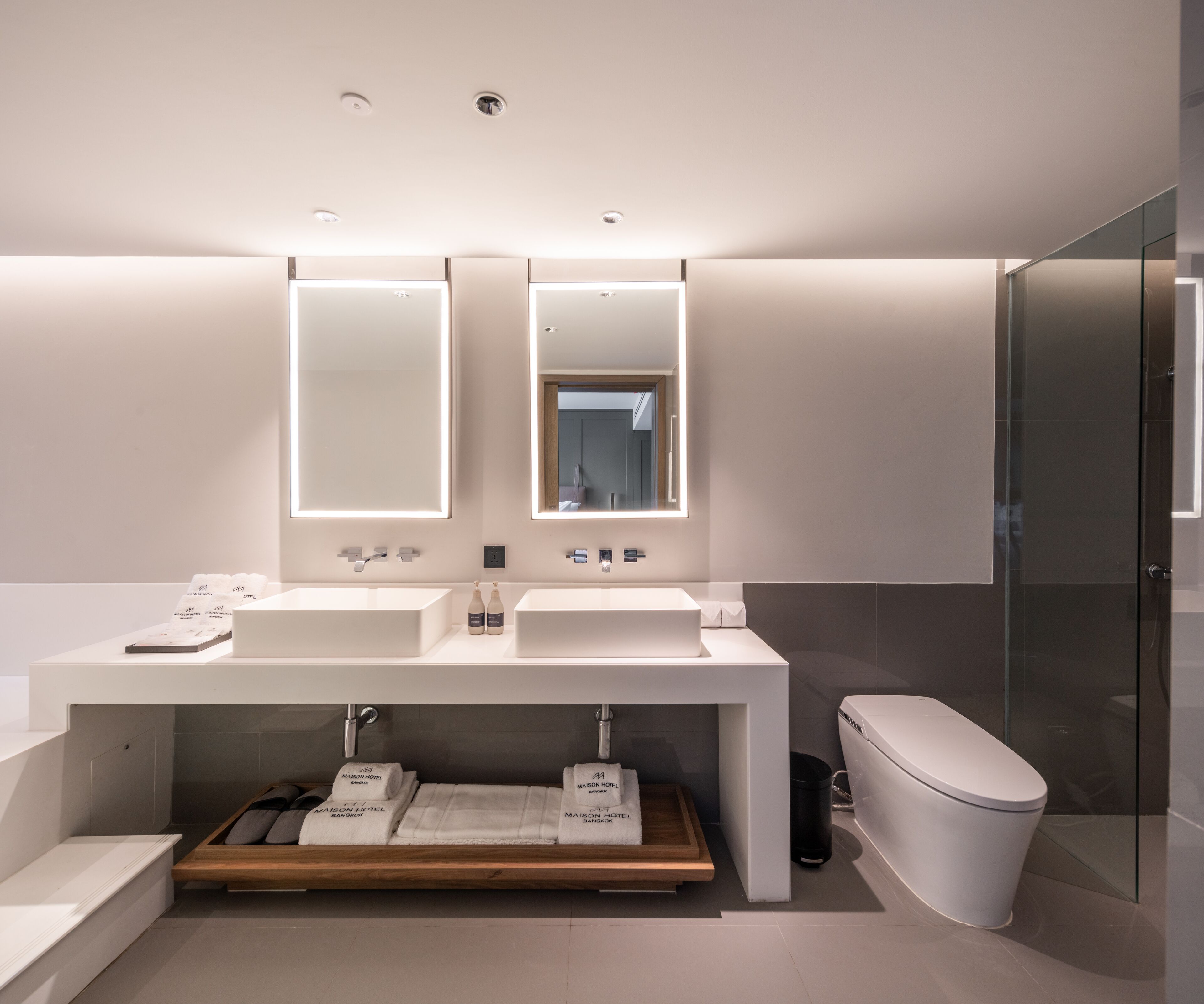 Une salle de bain moderne avec deux lavabos, un miroir et des toilettes.