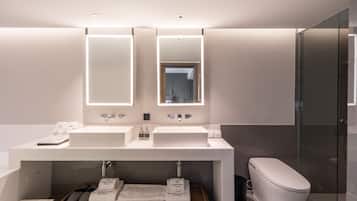 Une salle de bain moderne avec deux lavabos, un miroir et des toilettes.