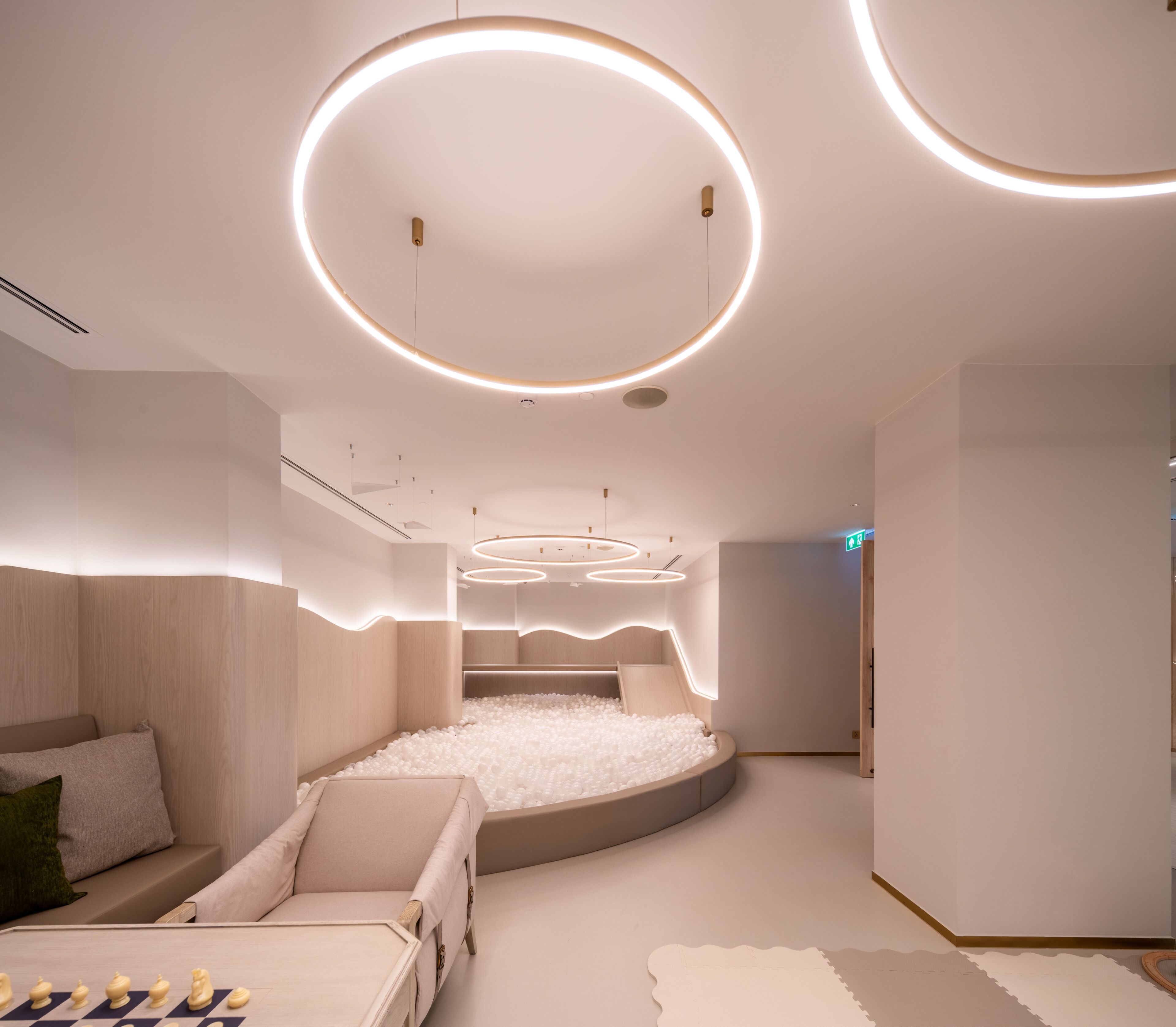 A modern hotel room with a circular bed, white walls, and a unique ceiling design.