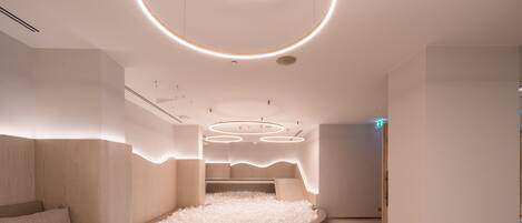 A modern hotel room with a circular bed, white walls, and a unique ceiling design.