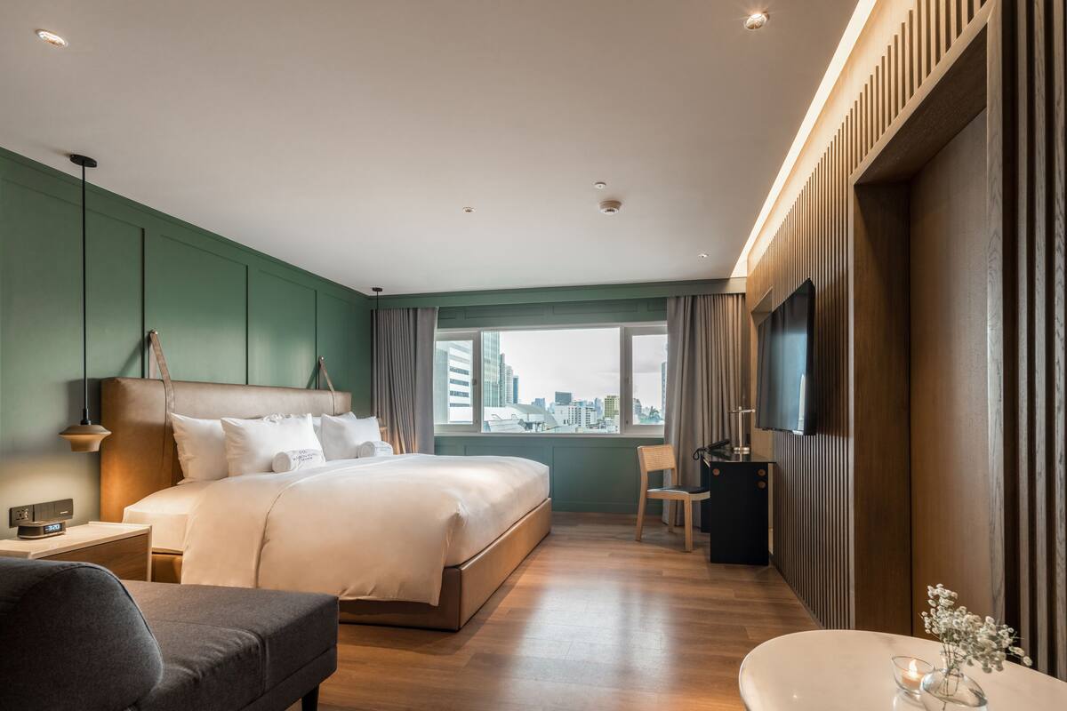 Une chambre d’hôtel moderne dotée d’un grand lit, d’un bureau, d’une chaise, d’une télévision et offrant une vue sur la ville.