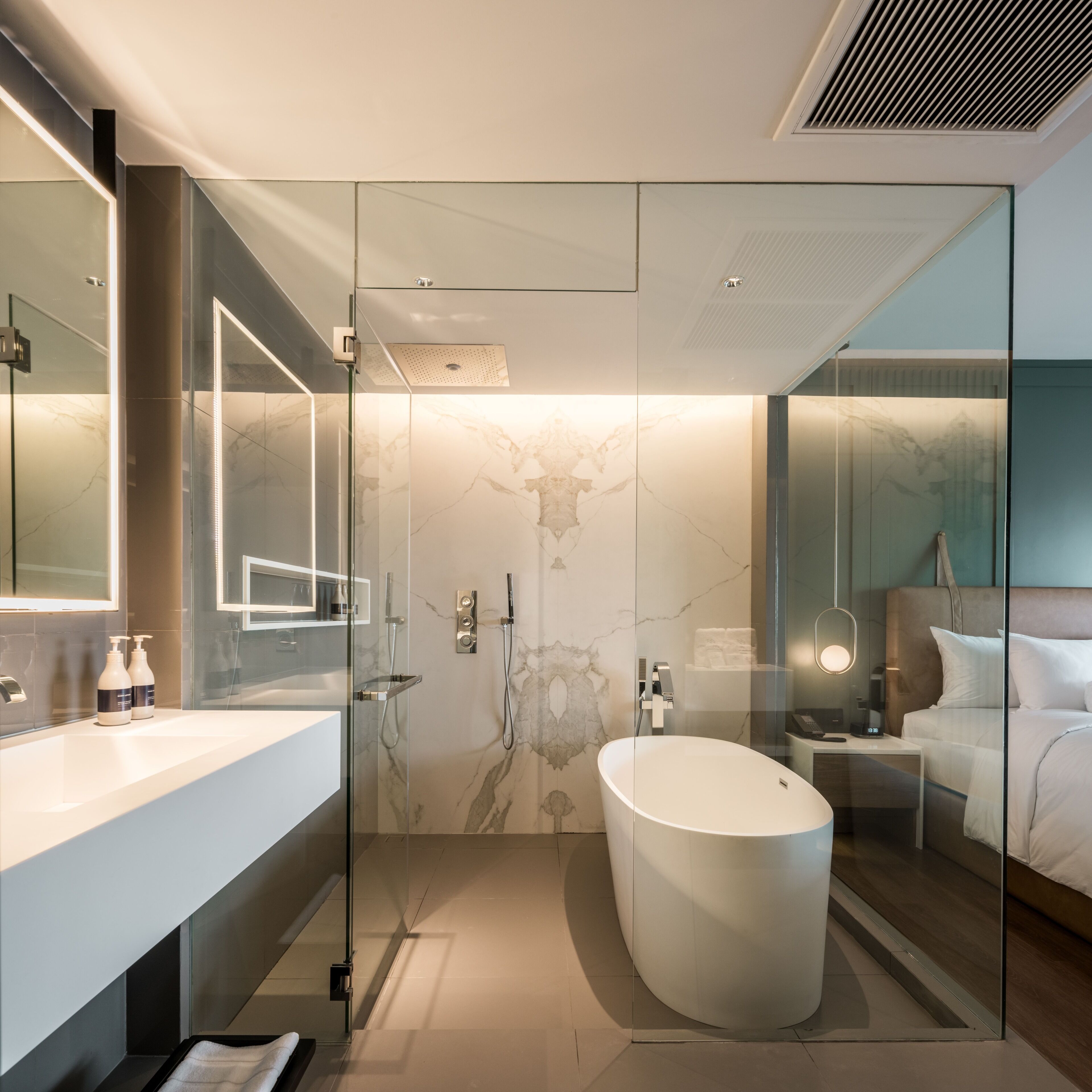 Une salle de bain moderne avec une douche à parois de verre, une baignoire sur pieds et un grand miroir.