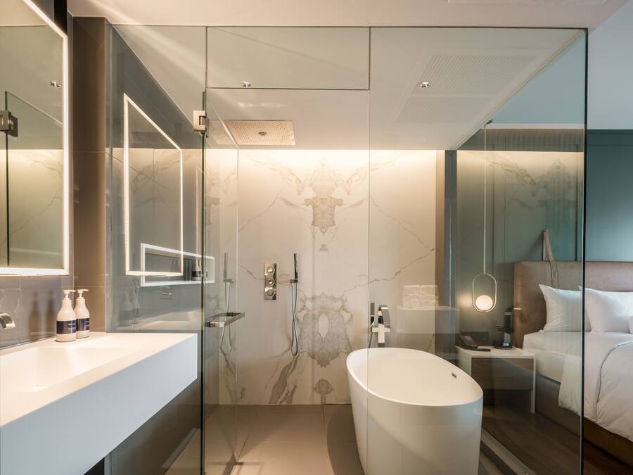 Ein modernes Badezimmer mit einer gläsernen Duschkabine, einer freistehenden Badewanne und einem großen Spiegel.