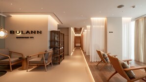 Un hall d’hôtel moderne au design minimaliste, comprenant un comptoir d’accueil, un espace salon et un escalier menant aux étages supérieurs.