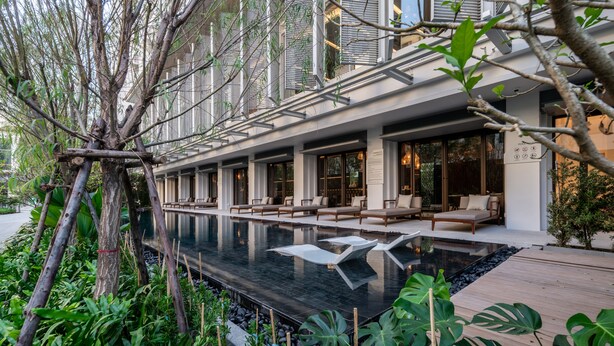 Un hôtel moderne doté d’une piscine, d’un espace extérieur aménagé et d’une végétation luxuriante.