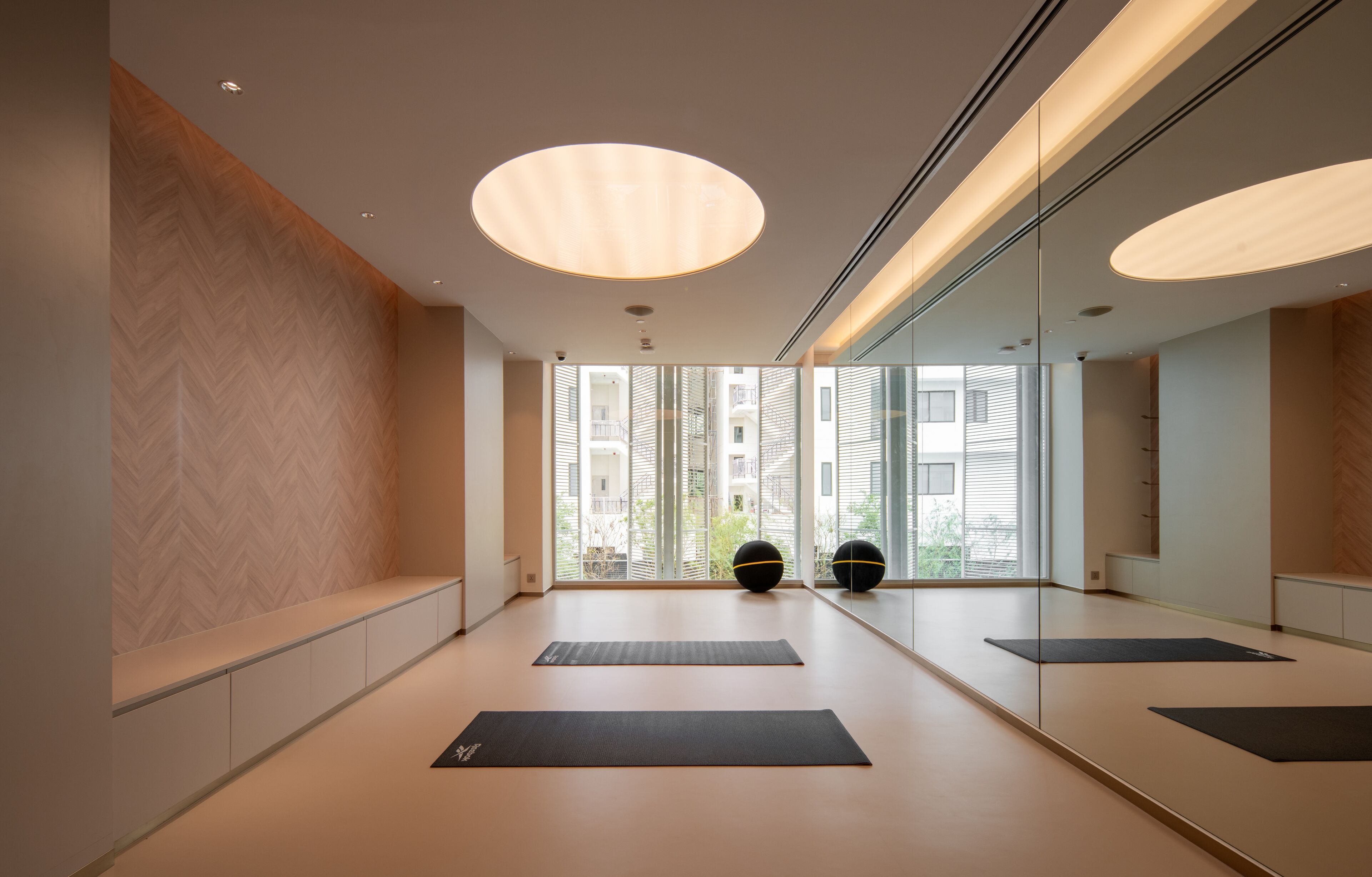 Un gimnasio moderno y minimalista con amplios ventanales, colchonetas de ejercicio y pelotas de entrenamiento.