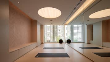Un gimnasio moderno y minimalista con amplios ventanales, colchonetas de ejercicio y pelotas de entrenamiento.