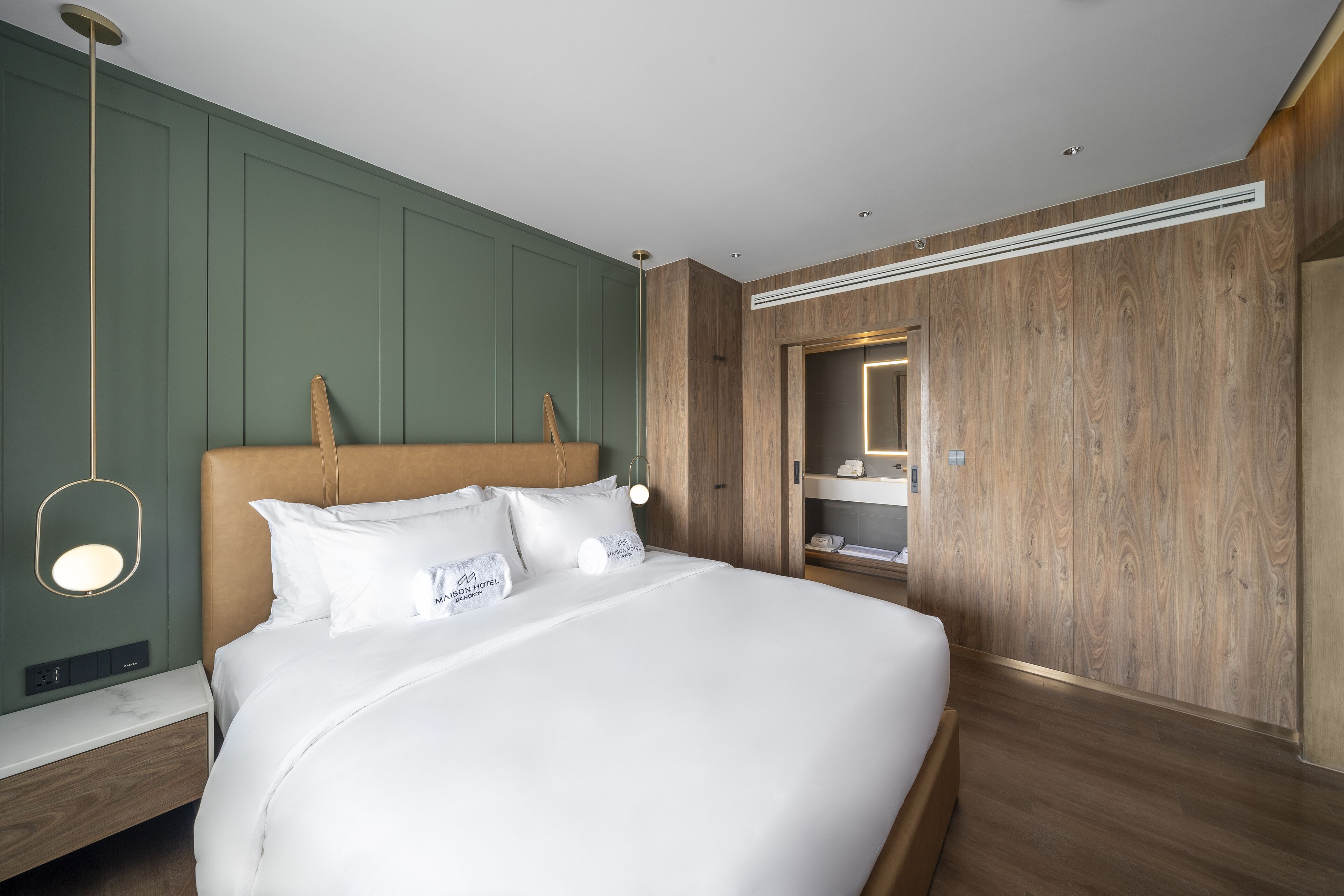 Una habitación de hotel moderna con una cama grande, cabecero de madera y una pared de acento verde.
