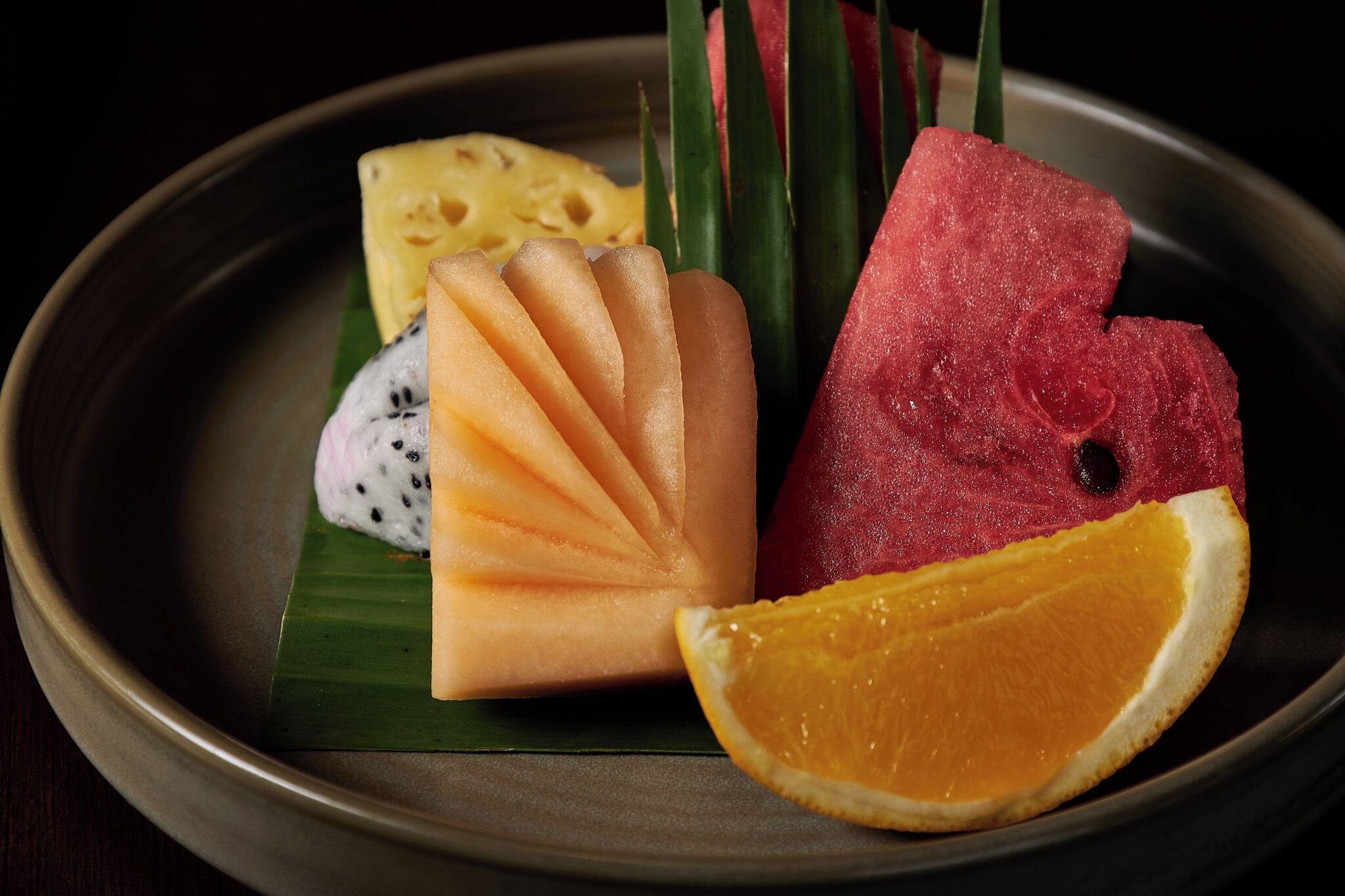 A plate with various fruits including watermelon, cantaloupe, pineapple, and orange slice.