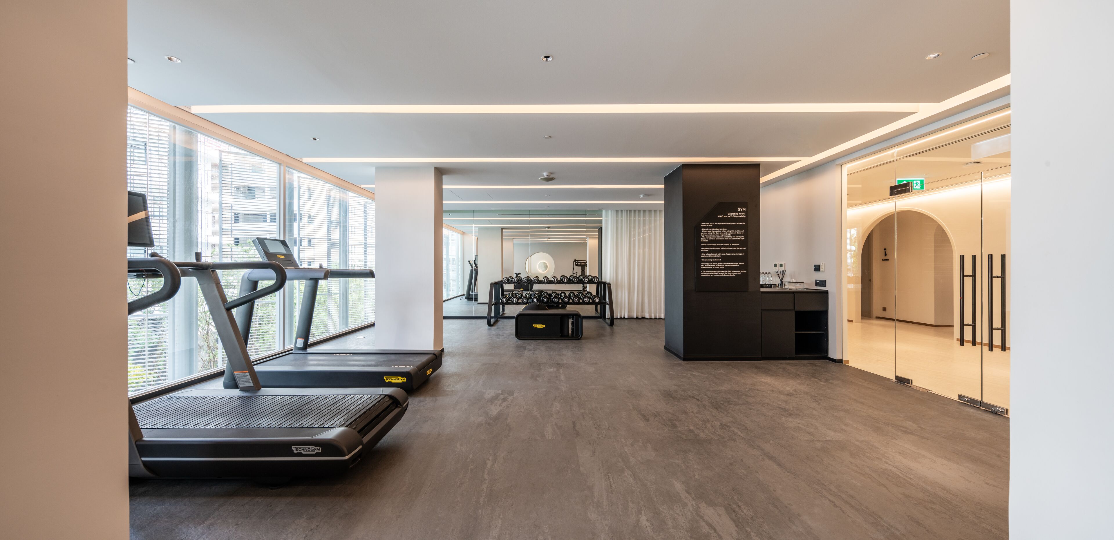 A modern gym with treadmills, a weight bench, and a mirror wall.