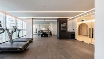 A modern gym with treadmills, a weight bench, and a mirror wall.