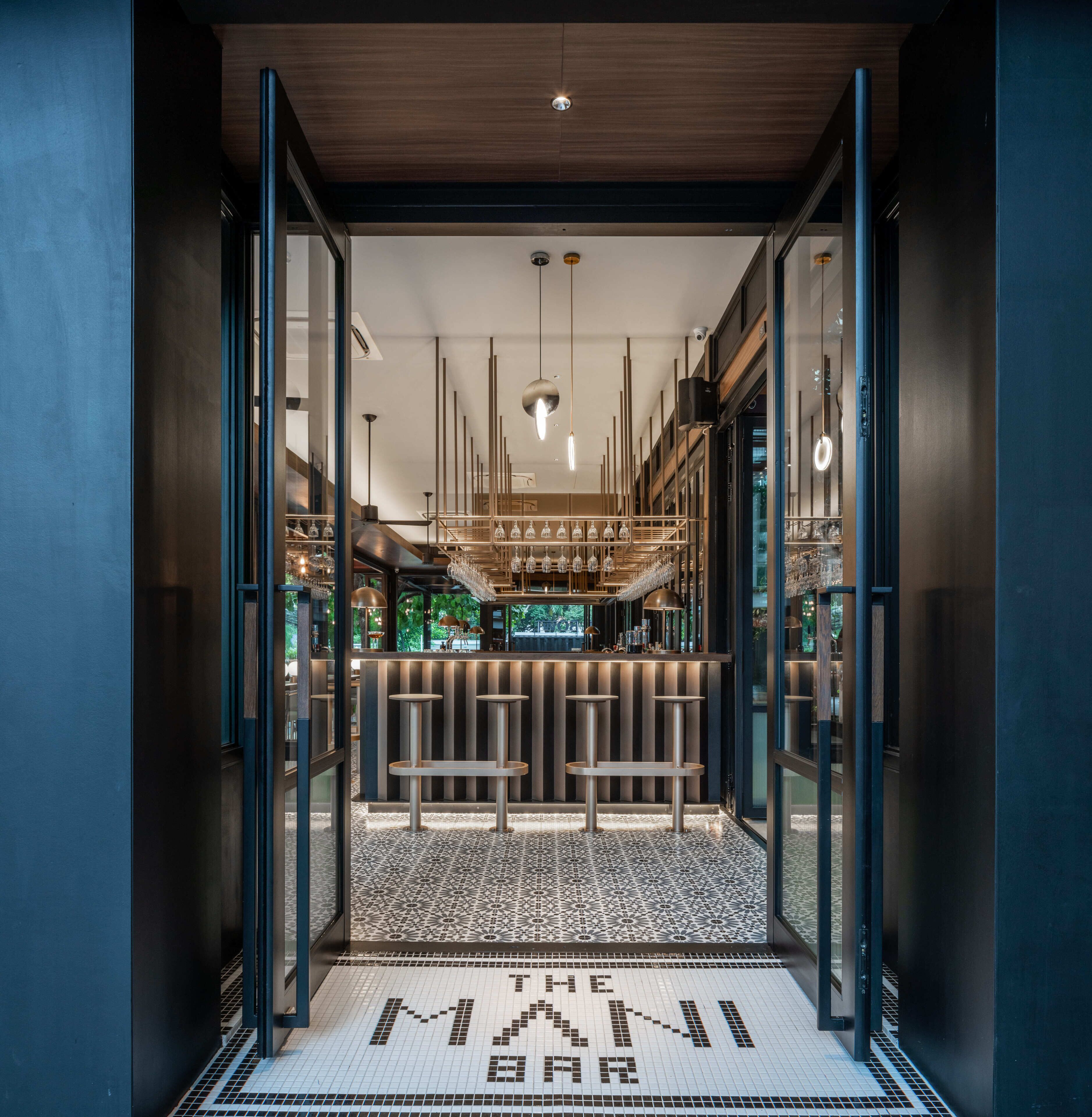 A modern bar with a patterned floor and a sign reading 'THE MANI BAR'.