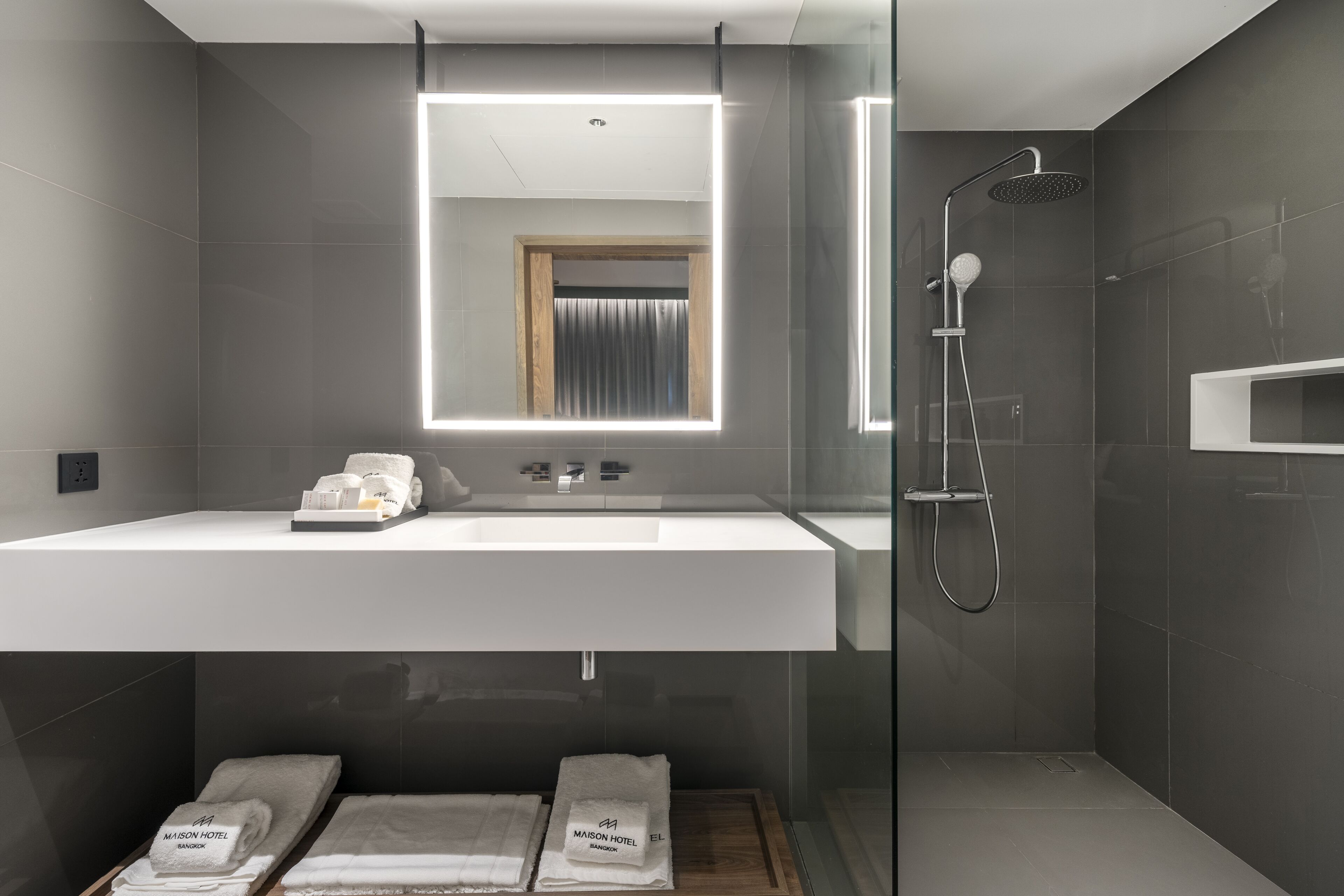 Une salle de bain moderne avec un grand miroir, une douche et un meuble-lavabo avec des serviettes.