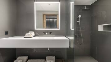 Une salle de bain moderne avec un grand miroir, une douche et un meuble-lavabo avec des serviettes.