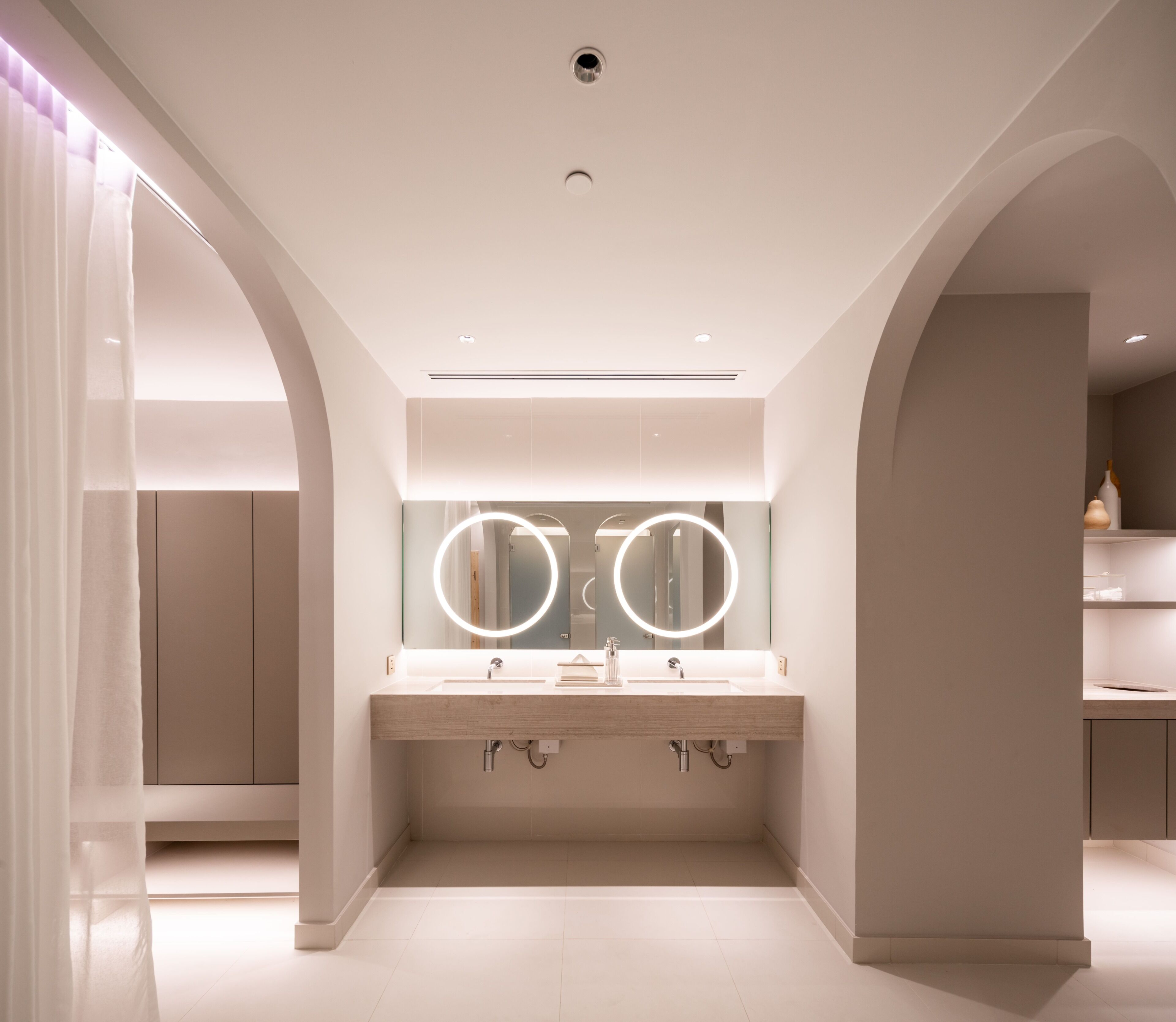 A modern bathroom with a double vanity, illuminated mirrors, and a clean, minimalist design.