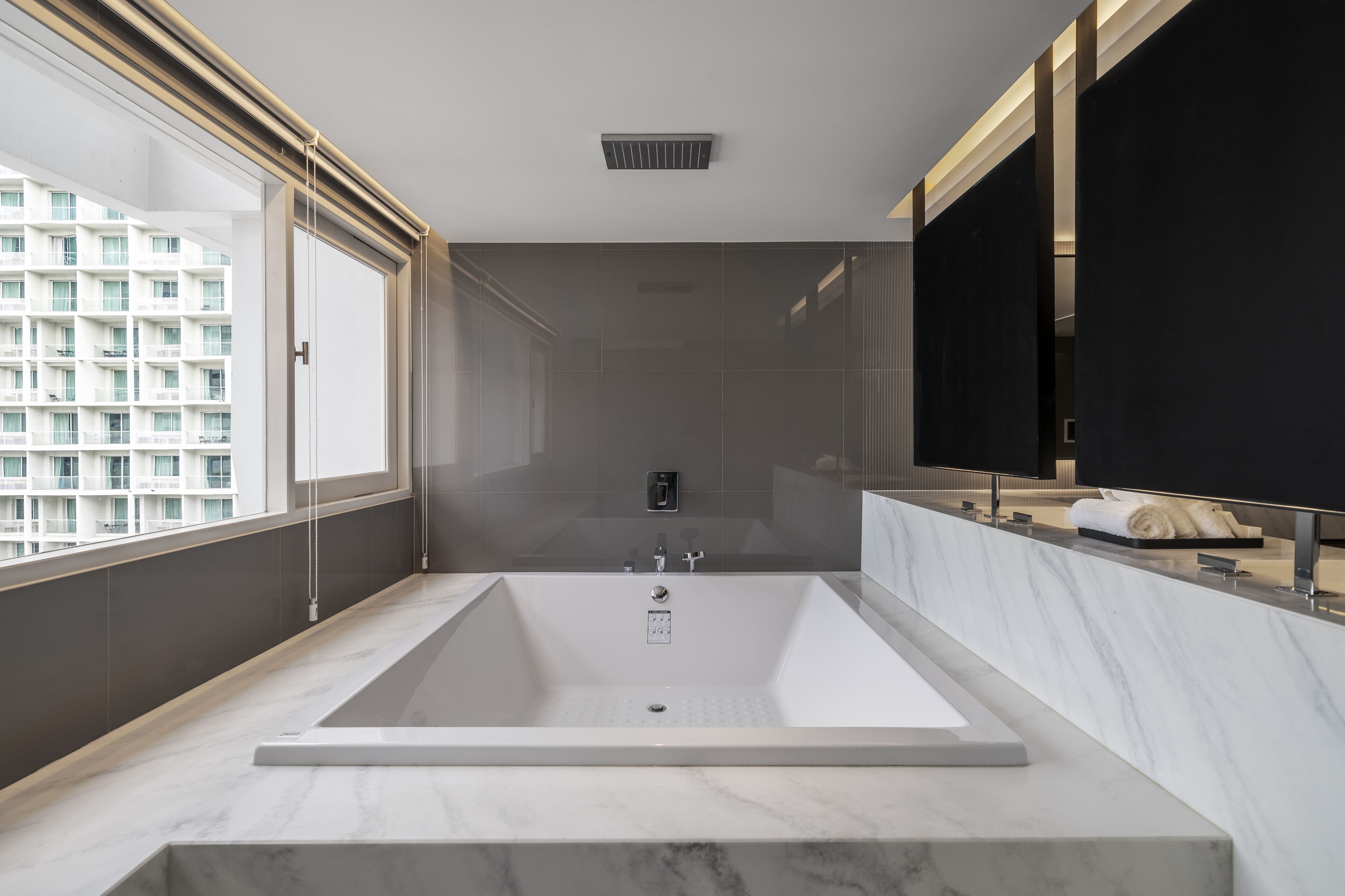 A modern bathroom with a large bathtub, a glass shower enclosure, and a large mirror.