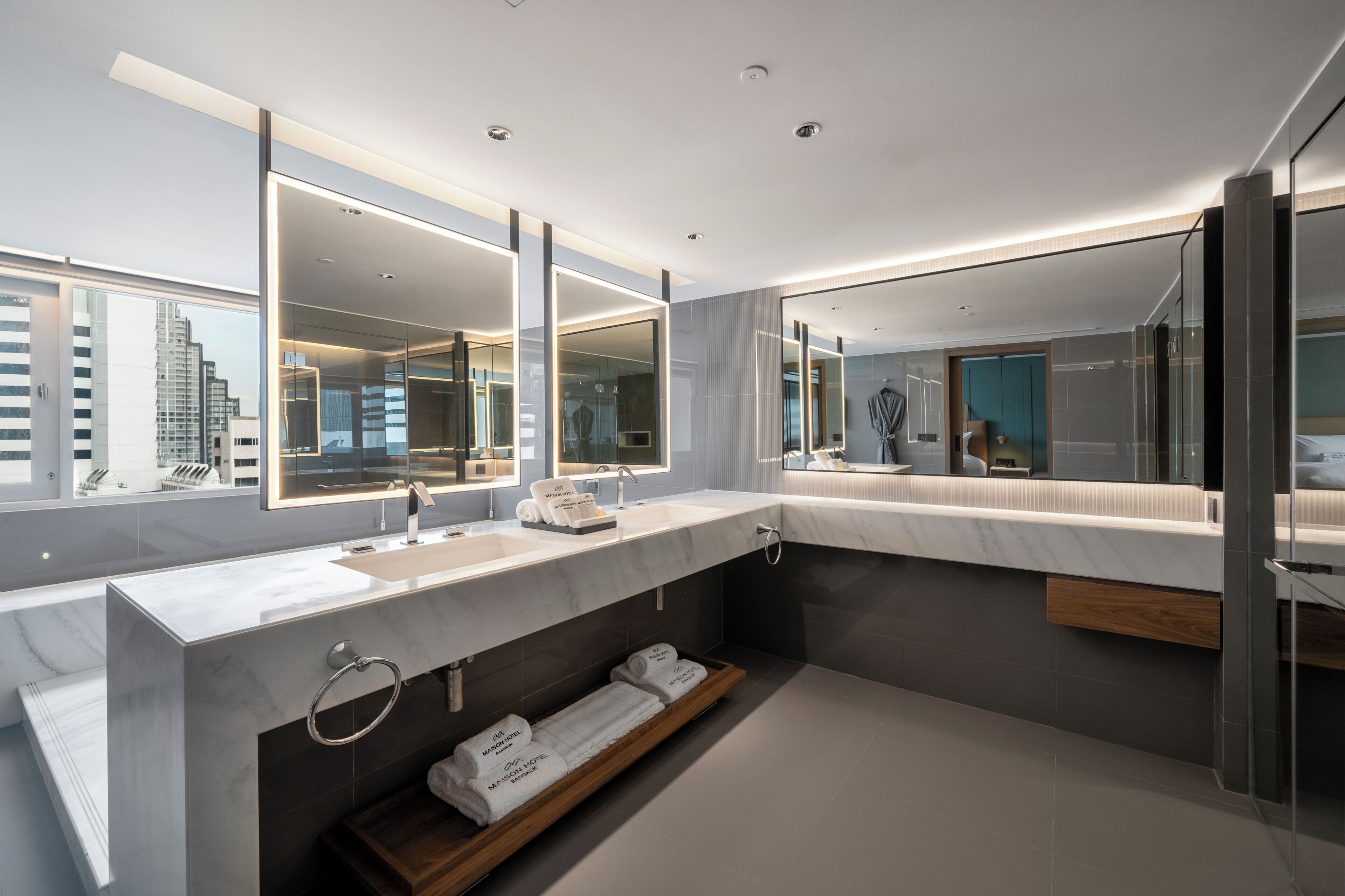 Un baño moderno con un espejo grande, lavamanos dobles y un perchero para toallas.