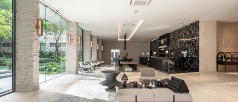 Un moderno vestíbulo de hotel con una amplia zona de estar, una recepción y vistas al exterior.