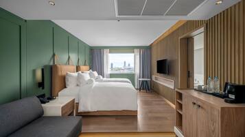 A hotel room with two beds, a sofa, a TV, and a city view.