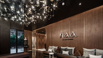 A modern interior with a wooden wall, a seating area with cushions, and a ceiling with hanging light fixtures.
