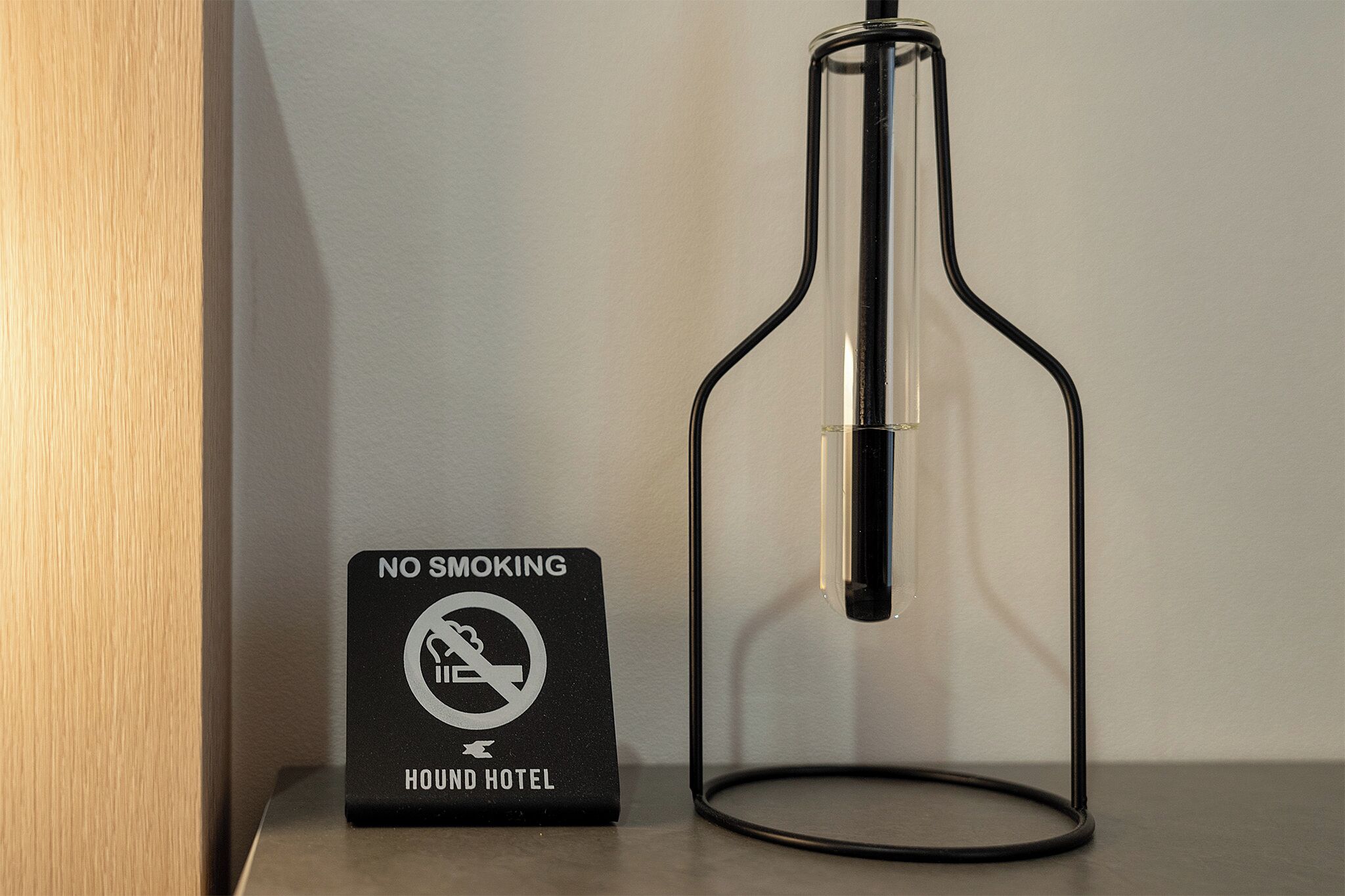 A no smoking sign and a clear glass bottle on a table.