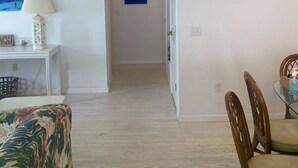 Ein Korridor mit einer Tür zu einem Zimmer, einem Bild an der Wand und einem Tisch mit Stühlen.