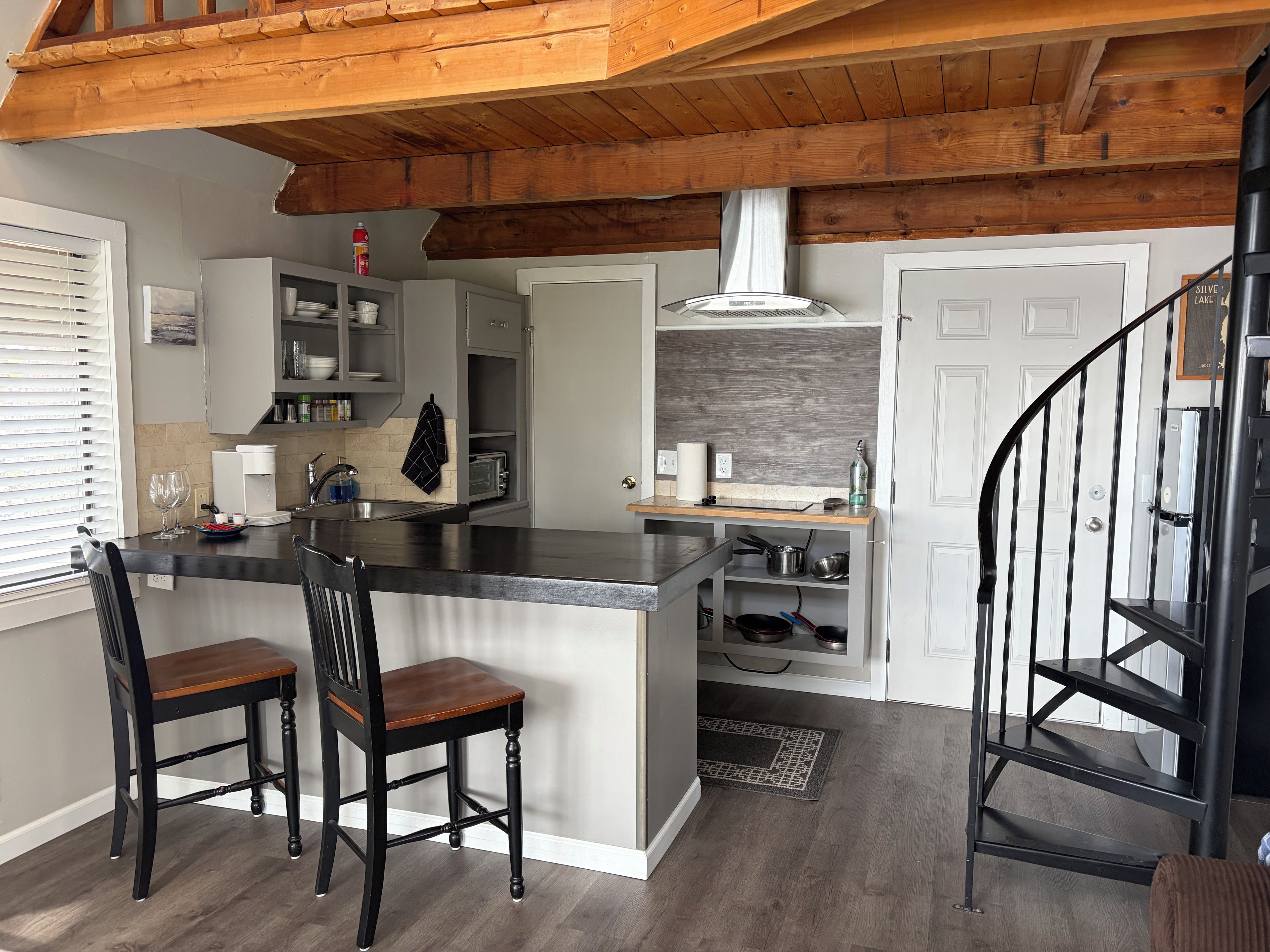 A kitchen with a central island, two bar stools, a microwave, and a stove.