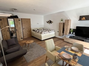 Una sala de estar moderna con un sofá, una mesa de comedor, un televisor y un mueble de madera.
