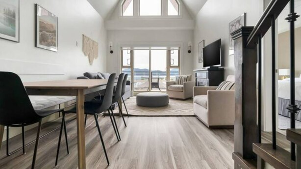 A modern living room with a dining area, large windows, and a view of the outdoors. - Harrison Hot Springs (Harrison Hot Springs)