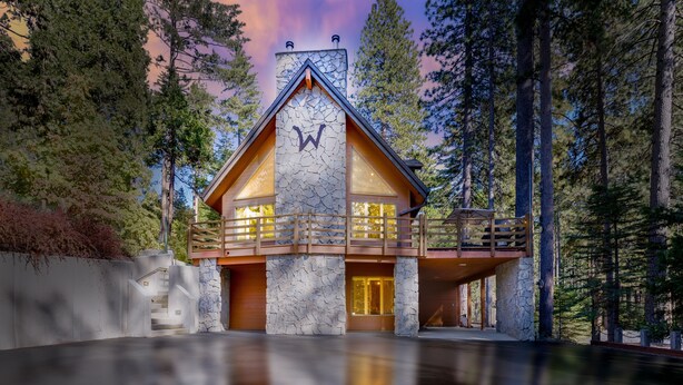 Une maison de style rustique moderne, avec une façade en pierre, un balcon en bois et une entrée en pierre.