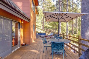 A wooden deck with outdoor furniture, including a table and chairs, and a large umbrella. - W House in BLS, Game Room, Fire Pit, Hot Tub, Central AC&Heat, Pet friendly! (Arnold)