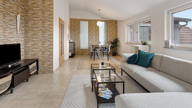 Un salon moderne comprenant un canapé, une table basse, un téléviseur et un coin repas avec des chaises et une table.