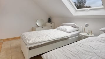 Een slaapkamer met twee bedden, een dakraam, een nachtkastje met een lamp en een kleine plant.