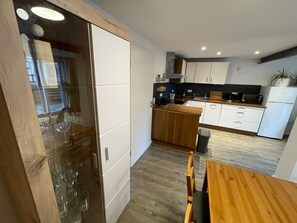 A modern kitchen with wooden cabinets, a dining table, and a trash bin. - Apartment "Happynest" with Balcony & Wi-Fi (Jena)