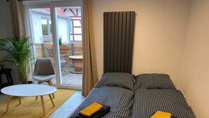 Huoneessa on sänky, pieni pöytä, tuoli ja ruukkukasvi.