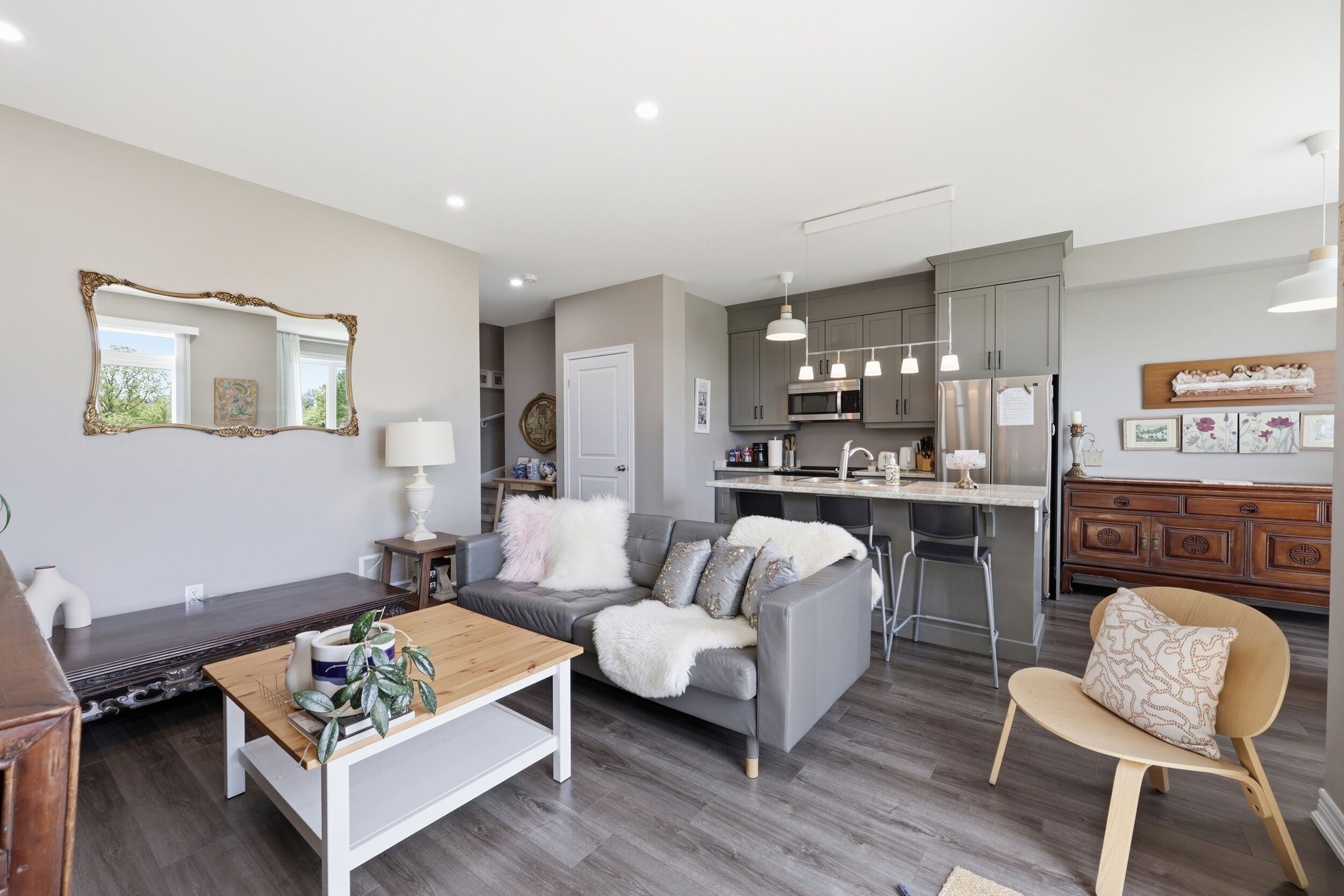 A modern living room with a sofa, coffee table, and a dining area with a kitchen in the background.