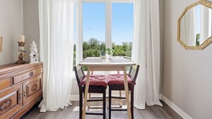 Ein Essbereich mit Tisch, Stühlen und Blick durch große Fenster.