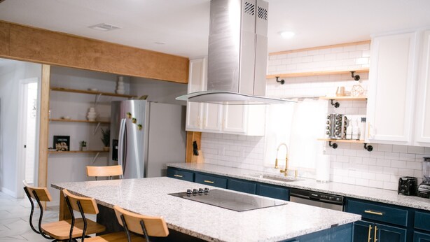 Une cuisine moderne dotée d’un îlot central, de tabourets de bar, d’une plaque de cuisson intégrée et d’un lave-vaisselle.