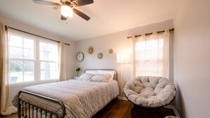 Une chambre à coucher avec un lit, une chaise, une lampe, une horloge et une fenêtre.