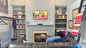 Una sala de estar acogedora con un sofá de cuero, una chimenea y estanterías llenas de libros.